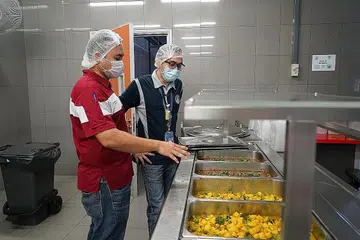 MAKANAN SESUAI: Encik Abubakar Siddiq Mohamed Idier (berbaju biru) sedang meninjau jenis makanan yang sesuai dengan diet para pekerja asing yang kebanyakannya datang dari bahagian selatan India.