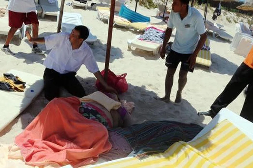 BERI BANTUAN: Lelaki warga Tunisia membantu seorang wanita yang cedera di bandar peranginan Sousse, 140 kilometer ke selatan ibukota Tunisia. Hampir 40 orang, sebilangan besar pelancong asing, terbunuh dalam serangan di pantai peranginan yang dipenuhi dengan pelancong yang sedang bercuti. - Foto AFP
