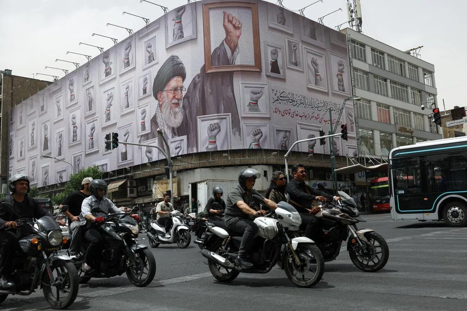 Orang ramai menunggang motosikal berhampiran papan iklan memaparkan imej mendiang Pemimpin Tertinggi Iran, Ayatollah Ali Khamenei, di Teheran, Iran, pada 19 Mei 2026.
