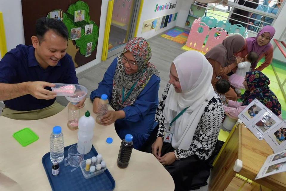KEMBANGKAN KHIDMAT: Encik Zaqy (kiri) mencuba kegiatan yang ditawarkan di bawah khidmat penjagaan bayi Iyad Perdaus di cawangan Choa Chu Kang semalam. - Foto BH oleh NG SOR LUAN