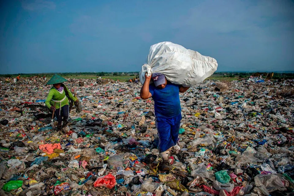 USAHA KURANGKAN SISA: Pengaut mengambil sisa di tempat buang sampah di Sidoarjo, Jawa Timur. Ulama kini mengadakan 'ngaji sampah' di seluruh Indonesia bagi meningkatkan kesedaran tentang pentingnya mengurangkan sisa plastik dan menjelaskan cara sisa plastik memburukkan bencana alam. - Foto AFP