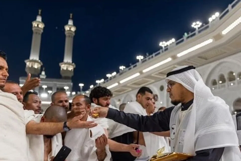 Sukarelawan mengagihkan manisan ketika umat Islam berhimpun menunaikan solat sunat Aidilfitri di Masjidil Haram, pada awal pagi 30 Mac sempena berakhirnya Ramadan.