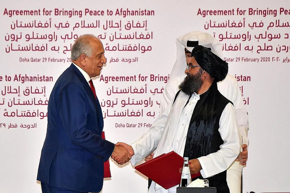 SETUJU DAMAI: Encik Zalmay Khalilzad (kiri) dan Mullah Abdul Ghani Baradar berjabat tangan selepas menandatangani perjanjian damai dalam satu majlis di Doha, Qatar baru-baru ini. - Foto AFP 