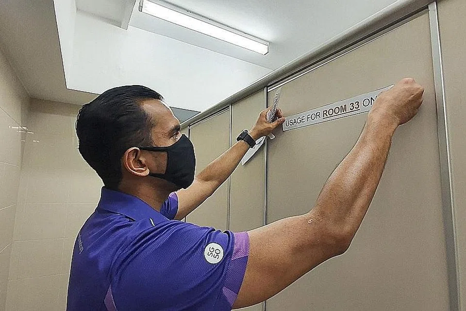 PASTIKAN JARAK SELAMAT: Demi mematuhi garis panduan jarak selamat, DSP Mohd Ilkhan sedang meletakkan pelekat agar kubikel tandas itu tidak boleh digunakan.