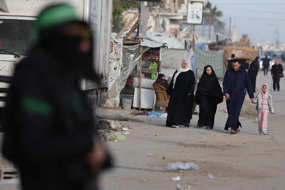 Seorang anggota Hamas Palestin berkawal ketika orang ramai berjalan di sebuah jalan sempena Hari Raya Aidilfitri di Bandar Gaza, 20 Mac 2026.