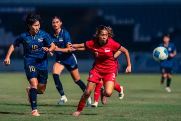 Pemain bola sepak wanita Singapura, Seri Nurinsyirah Indra Saharen (kanan) diasak oleh pemain Thailand dalam perlawanan Sukan SEA. Skuad Singa tewas 0-2.