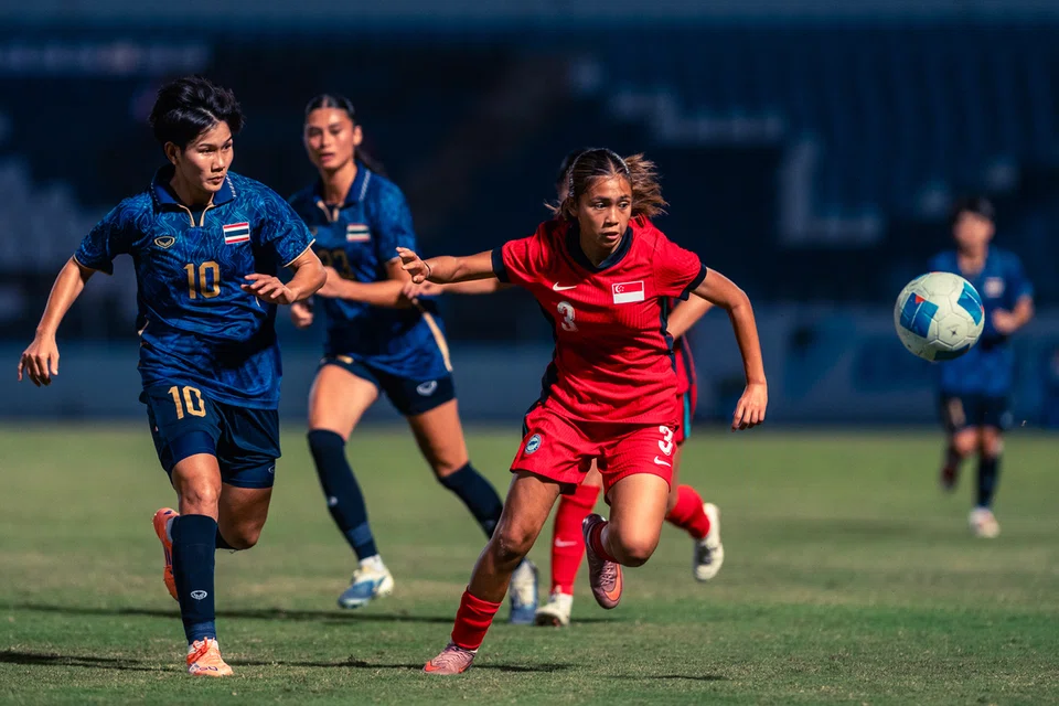 Pemain bola sepak wanita Singapura, Seri Nurinsyirah Indra Saharen (kanan) diasak oleh pemain Thailand dalam perlawanan Sukan SEA. Skuad Singa tewas 0-2.