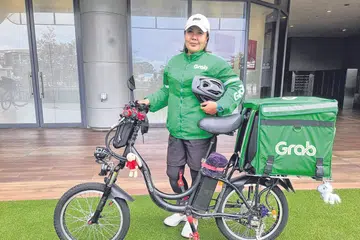 HARAP PERLINDUNGAN DAPAT DISEDIAKAN: Pekerja penghantaran GrabFood, Cik Nuraini Mohd Yusof, berharap bantuan dan perlindungan dapat disediakan kepada golongan pekerja seperti beliau yang bekerja tanpa kontrak pekerjaan dan perlu mengharungi pelbagai cabaran di luar kawalan mereka. - Foto ihsan NURAINI MOHD YUSOF