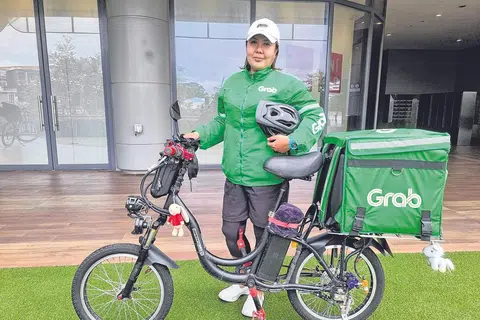 HARAP PERLINDUNGAN DAPAT DISEDIAKAN: Pekerja penghantaran GrabFood, Cik Nuraini Mohd Yusof, berharap bantuan dan perlindungan dapat disediakan kepada golongan pekerja seperti beliau yang bekerja tanpa kontrak pekerjaan dan perlu mengharungi pelbagai cabaran di luar kawalan mereka. - Foto ihsan NURAINI MOHD YUSOF