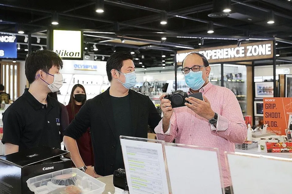 GIATKAN PENDIGITALAN: Encik Iswaran (kanan) meninjau kamera yang dijual di kedai milik Pengarah Urusan T K Foto, Encik James Ng (tengah). Kedai yang terletak di Funan Mall itu telah mendigitalkan perniagaannya, dengan menawarkan wadah e-niaga semasa Covid-19. - Foto BH oleh GAVIN FOO