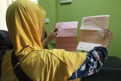 Seorang ibu membelek dokumen rumah HDB miliknya (gambar hiasan)