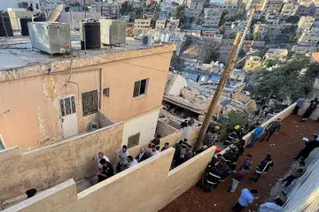 CARI MANGSA: Anggota pasukan pertahanan awam sedang mencari mangsa yang mungkin masih terperangkap di bawah runtuhan di sebuah bangunan yang runtuh di Amman, Jordan. - Foto REUTERS