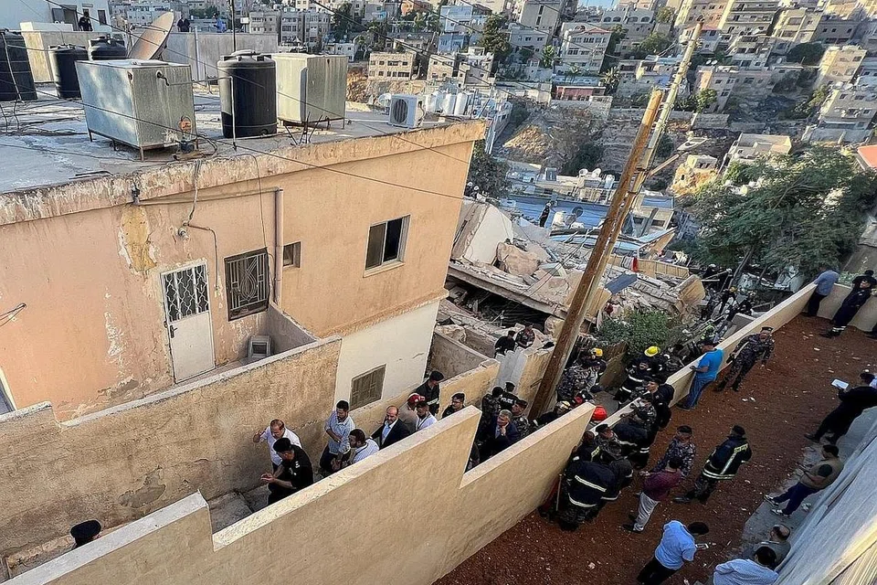 CARI MANGSA: Anggota pasukan pertahanan awam sedang mencari mangsa yang mungkin masih terperangkap di bawah runtuhan di sebuah bangunan yang runtuh di Amman, Jordan. - Foto REUTERS