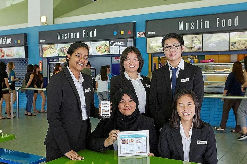 MISI BANGUN 'KANTIN BIJAK' : (Dari kiri) Cik Amulya Gamane, Cik Nur Diyanah Razali (duduk), Cik Lee Hui Shi, Encik Joel Ten dan Cik Foo Yan Xi bertuah dapat menggabungkan kemahiran teknologi maklumat dan perniagaan dalam projek tahun akhir yang memudahkan urusan jual beli kantin sekolah. - Foto POLITEKNIK TEMASEK
