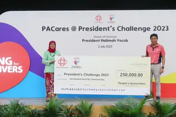 SOKONGAN BAGI CABARAN PRESIDEN: Presiden Halimah Yacob menerima cek sumbangan Persatuan Rakyat (PA) daripada Ketua Pengarah Eksekutif Encik Jimmy Toh, di Kelab Masyarakat Hong Kah North pada 2 Julai 2023.
