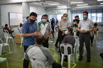 VAKSINASI PEKERJA PENGANGKUTAN DARAT: Encik Chee Hong Tat (kiri) bersama Setiausaha Eksekutif Kesatuan Pekerja Pengangkutan Kebangsaan, Encik Melvin Yong, berinteraksi dengan beberapa pekerja pengangkutan darat. - Foto BH oleh ARIFFIN JAMAR 