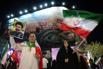 Seorang lelaki Iran memegang potret Pemimpin Tertinggi Iran, Ayatollah Mojtaba Khamenei, semasa tunjuk perasaan pada waktu malam membantah Amerika Syarikat di Teheran pada 26 Ogos 2026. Demonstrasi itu diadakan selepas Washington mengumumkan sekatan baharu menerusi kempen ekonomi yang bertujuan menyekat hubungan kewangan Iran dengan sistem kewangan global. Teheran berikrar akan bertindak balas terhadap langkah tersebut.