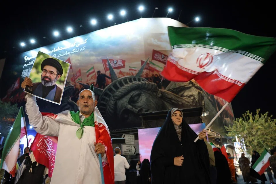 Seorang lelaki Iran memegang potret Pemimpin Tertinggi Iran, Ayatollah Mojtaba Khamenei, semasa tunjuk perasaan pada waktu malam membantah Amerika Syarikat di Teheran pada 26 Ogos 2026. Demonstrasi itu diadakan selepas Washington mengumumkan sekatan baharu menerusi kempen ekonomi yang bertujuan menyekat hubungan kewangan Iran dengan sistem kewangan global. Teheran berikrar akan bertindak balas terhadap langkah tersebut.