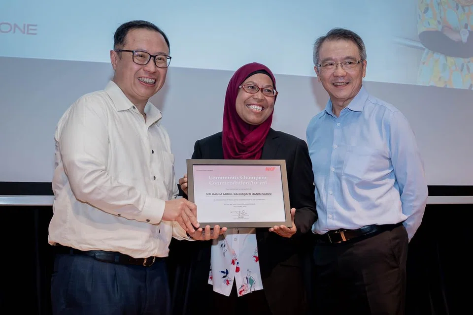 Cik Siti Hanim Abdul Rahim @ Siti Hanim Sarjo menerima Anugerah Juara Komuniti sempena acara Yayasan Buah Pinggang Kebangsaan (NKF) bagi memperingati 55 tahun Memberi Kehidupan & Harapan, disampaikan oleh Pengerusi NKF, Encik Arthur Lang (kiri) dan Encik Tim Oei, Ketua Pegawai Eksekutif NKF.