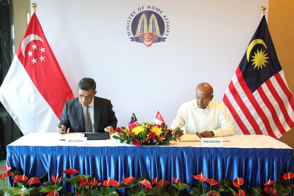Menteri Ehwal Dalam Negeri, Encik K. Shanmugam (kanan) menandatangani MOU dengan rakan seangkatan dari Malaysia, Datuk Seri SAifuddin Nasution Ismail.