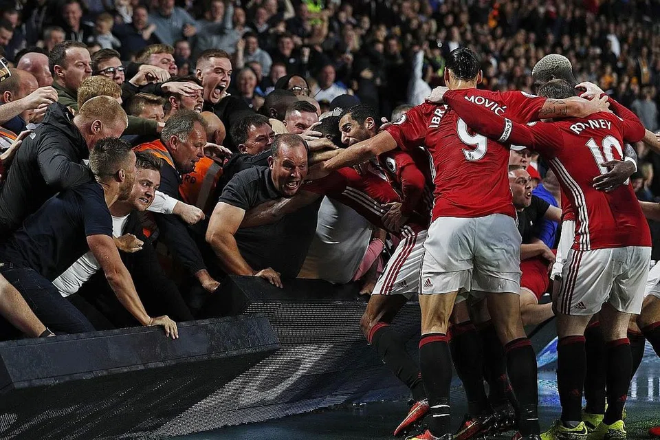 WIRA 'DISERBU': Wira Manchester United, Marcus Rashford (terselindung), meraikan golnya dengan para penyokong pasukan. `