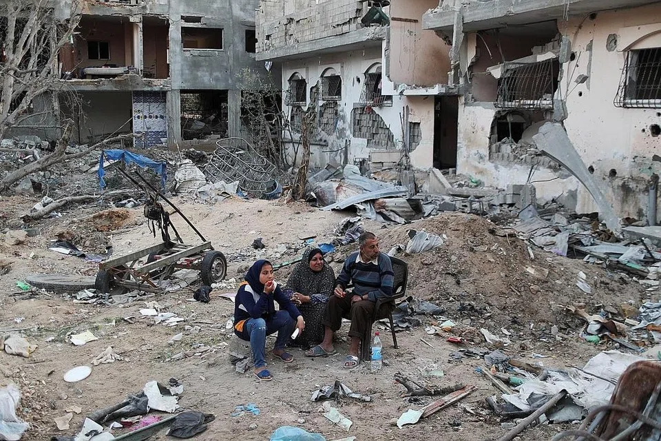 NASIB DIJAJAH: Rakyat Palestin di Jaluran Gaza duduk di kawasan lapang dikelilingi timbunan runtuhan rumah dan bangunan yang musnah akibat bedilan bom tentera Israel semasa perang yang diakhiri dengan gencatan senjata pada 1 Mei lalu. - Foto REUTERS