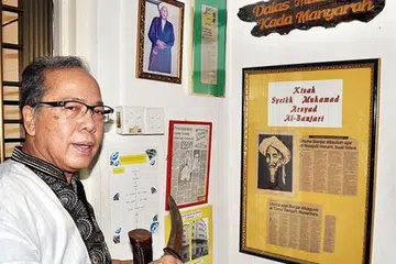 PASTIKAN WARISAN DAN SEJARAH ORANG BANJAR TERPELIHARA: Encik Abdul Latiff memegang beladau yang diwarisi turun-temurun di sudut sejarah orang Banjar di flatnya di Pasir Ris. - Foto JOHARI RAHMAT