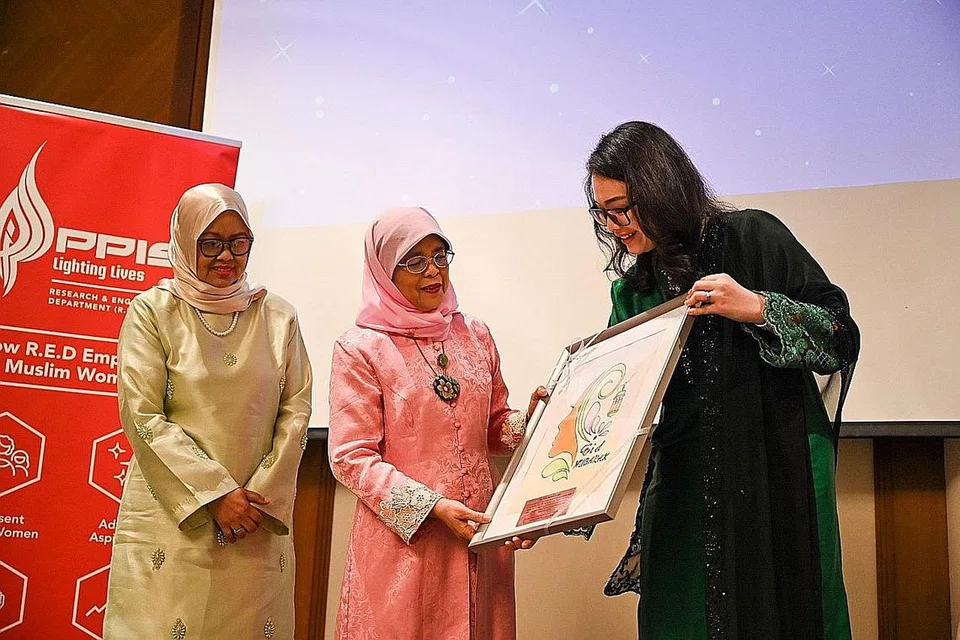 TANDA PENGHARGAAN: Presiden Halimah Yacob (tengah) menerima lukisan hasil karya penghuni Rumah Peralihan Rise Above kendalian PPIS daripada Cik Hazlina Abdul Halim (kanan) sambil disaksikan CEO PPIS, Cik Tuminah Sapawi. - Foto BH oleh SHAFIQ APANDI