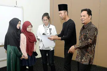 MENGHAYATI SASTERA KLASIK: Encik Roslan Madun (kanan) mengajak peserta bengkel, (dari kiri) Nur Shafiqah Abdullah, Nabila Siddiq dan Hanisah Hamizah Hamzah, membaca syair yang pelbagai irama dengan dibantu Encik Hanafi Idrus, aktivis budaya setempat. - Foto JOHARI RAHMAT