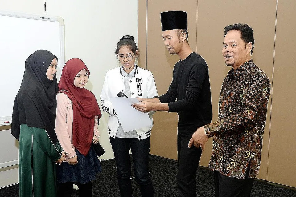 MENGHAYATI SASTERA KLASIK: Encik Roslan Madun (kanan) mengajak peserta bengkel, (dari kiri) Nur Shafiqah Abdullah, Nabila Siddiq dan Hanisah Hamizah Hamzah, membaca syair yang pelbagai irama dengan dibantu Encik Hanafi Idrus, aktivis budaya setempat. - Foto JOHARI RAHMAT