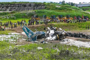 Anggota tentera dan para pegawai lain berdiri mengelilingi bangkai pesawat Saurya Airlines yang terhempas ketika sedang berlepas di Lapangan Terbang Antarabangsa Tribhuvan di Kathmandu, Nepal, pada 24 Julai.