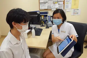 MANFAATKAN TEKNOLOGI: Seorang jururawat poliklinik menggunakan sistem saringan dan klasifikasi bijak di iPad untuk membantu menilai sama ada seorang pesakit yang mengalami sakit dada menghidap penyakit jantung koronari. - Foto SINGHEALTH POLYCLINICS