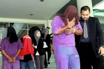 DITAHAN: Beberapa pegawai SPRM mengiring keluar empat pegawai Jabatan Imigresen Selangor dari Mahkamah Majistret Shah Alam. - Foto THE STAR