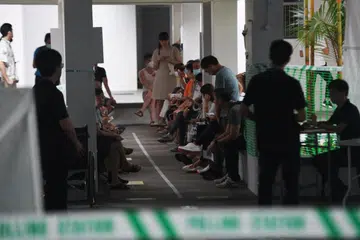 SABAR MENANTI: Orang ramai dilihat menanti di luar Pusat Mengundi di Blok 81B, Toa Payoh Lorong 4 pada 7.55 pagi.