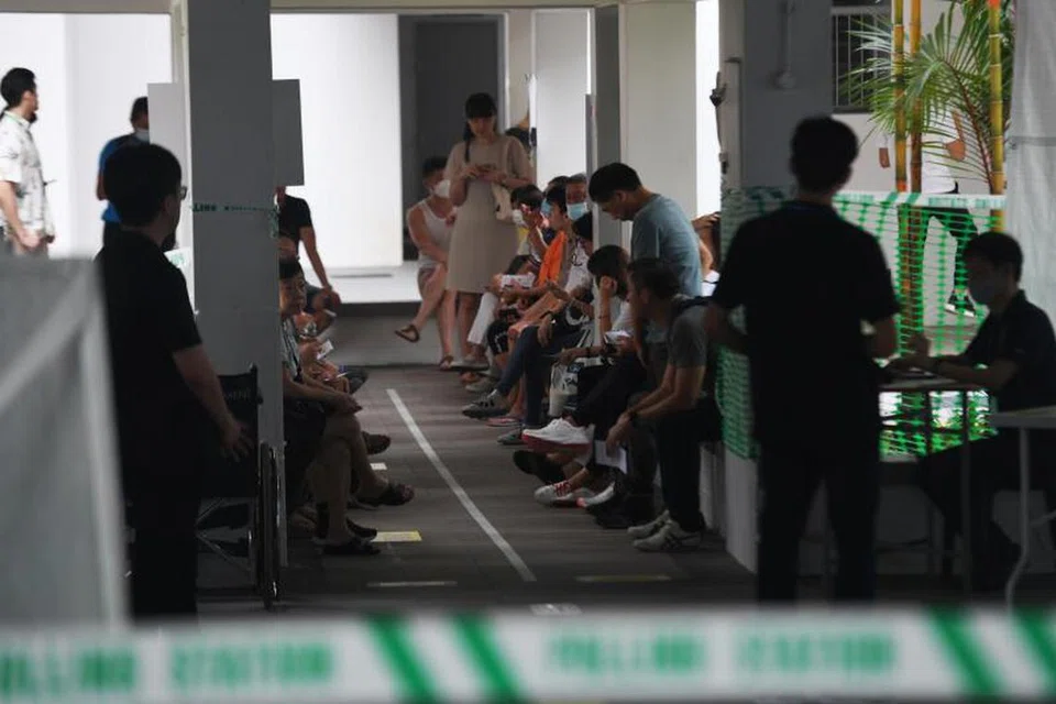 SABAR MENANTI: Orang ramai dilihat menanti di luar Pusat Mengundi di Blok 81B, Toa Payoh Lorong 4 pada 7.55 pagi.
