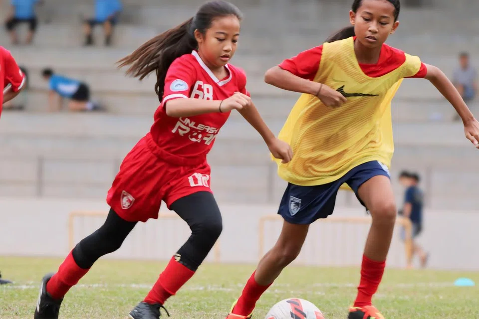 GIGIH BERLATIH: Nufah Asyura Mohamad Hisham (kiri), 12 tahun, berlatih bersama pasukan Pusat Pembangunan Nasional (NDC) U-13, dan mewakili mereka dalam Liga Belia Singapura.