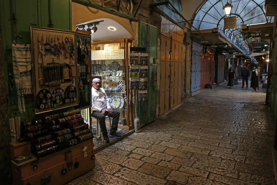 Seorang lelaki duduk di luar kedainya di tengah-tengah kedai yang kebanyakannya ditutup di lorong Kota Lama Baitulmakdis, pada 11 September sedang Pertubuhan Bangsa-Bangsa Bersatu (PBB) memberi amaran bahawa konflik berterusan Gaza telah menjejas kegiatan ekonomi. 