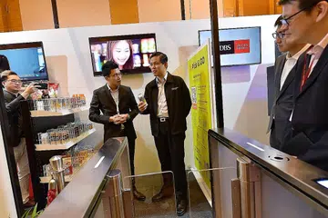 KEDAI GENERASI BARU: Encik Chan (memegang sebuah produk) mengunjungi reruai yang memaparkan konsep kedai tanpa pekerja di Persidangan dan Pameran Industri Runcit Singapura semalam. - Foto NG SOR LUAN