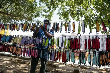 JUAL PELITUP: Seorang peniaga jalanan sedang mengatur pelitup di kedainya di bandar Hyderabad sebagai sebahagian usaha mencegah penularan Covid-19 di India. - Foto AFP