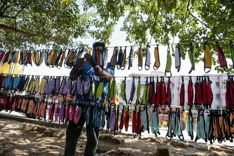JUAL PELITUP: Seorang peniaga jalanan sedang mengatur pelitup di kedainya di bandar Hyderabad sebagai sebahagian usaha mencegah penularan Covid-19 di India. - Foto AFP