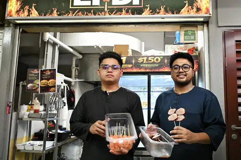 Dua beradik, Encik Muhammad Syafiq Jafni Jasmani (kiri) dan Encik Aniq Nazirul Hasri, akan memulakan sambutan Hari Raya pertama sebagai pemilik gerai makanan di pusat penjaja. 