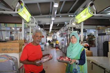 DUA GERAI ADA E-PEMBAYARAN: Cik Rahima Beevi dan bapanya, Encik Mohd Faruk, mengendali dua gerai di Pasar Pek Kio. Cik Rahima pemilik gerai Tazmeen Beef Stall yang menjual daging lembu, manakala bapanya, pemilik gerai Faraz Ahmed Mutton Stall, menjual ayam dan daging kambing. Mereka berdua menawarkan kaeadah e-pembayaran kepada pelanggan. - Foto BH oleh ONG WEE JIN
