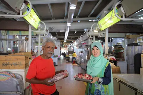 DUA GERAI ADA E-PEMBAYARAN: Cik Rahima Beevi dan bapanya, Encik Mohd Faruk, mengendali dua gerai di Pasar Pek Kio. Cik Rahima pemilik gerai Tazmeen Beef Stall yang menjual daging lembu, manakala bapanya, pemilik gerai Faraz Ahmed Mutton Stall, menjual ayam dan daging kambing. Mereka berdua menawarkan kaeadah e-pembayaran kepada pelanggan. - Foto BH oleh ONG WEE JIN
