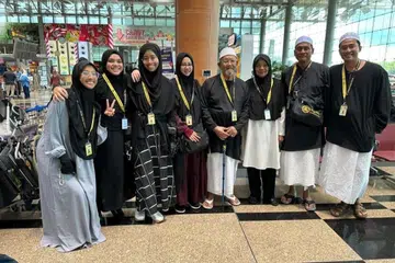 MASIH MENANTI:  Encik Muhammad Shodiqin Abdul Jalil (kanan) bersama ahli keluarganya bergambar bersama di Lapangan Terbang Changi pada Jumaat lalu, tarikh asal mereka sepatutnya berlepas ke Jeddah.