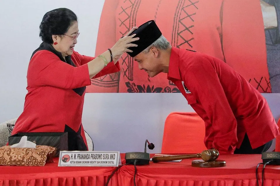 BEROLEH RESTU: Ketua Umum PDI-P, Cik Megawati Sukarnoputri, juga mantan presiden Indonesia kelima (2001-2004) memakaikan songkok ke kepala Gabenor Jawa Tengah, Encik Ganjar Pranowo, selepas parti itu memilihnya sebagai calon presiden untuk pilihan raya presiden 2024, dalam satu majlis di Bogor, Jawa Barat, pada 21 April 2023. - Foto AFP