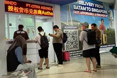 Penumpang beratur di kaunter perkhidmatan di Terminal Feri Antarabangsa Batam Centre ketika operator feri mengurangkan kekerapan perjalanan ke Singapura susulan lonjakan harga bahan api.
