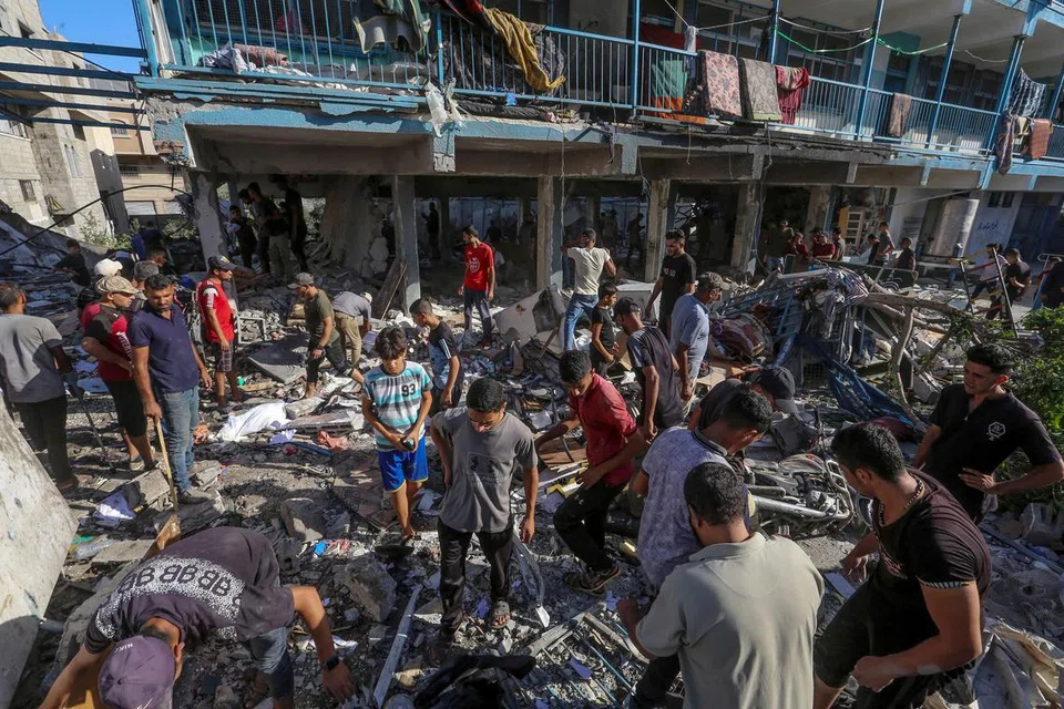 Para penduduk Palestin mencari mereka yang mungkin tertimbus di bawah runtuhan bangunan ekoran serangan udara Israel ke atas sebuah sekolah yang dijadikan tempat perlindungan pelarian Palestin di Nuseirat di tengah Gaza pada 11 September.