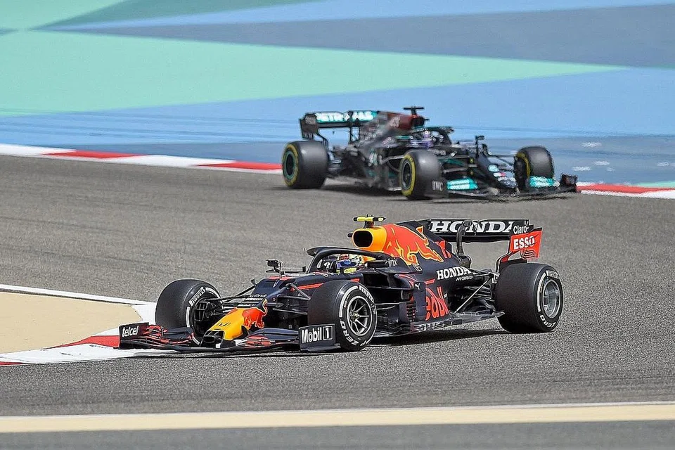 PERSAINGAN ANTARA RED BULL DENGAN MERCEDES: Pemandu Red Bull Sergio Perez (kereta depan) mendahului juara dunia tujuh kali Lewis Hamilton dalam kereta Mercedes (di belakang) pada hari kedua latihan di Litar Antarabangsa Sakhir, Bahrain, pada 13 Mac lalu. - Foto AFP