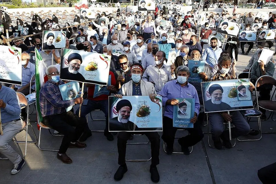 RAMAI PENYOKONG: Penduduk setempat memegang gambar Encik Ebrahim Raisi semasa kempen pilihan raya di Teheran pada 14 Jun lalu. - Foto EPA-EFE