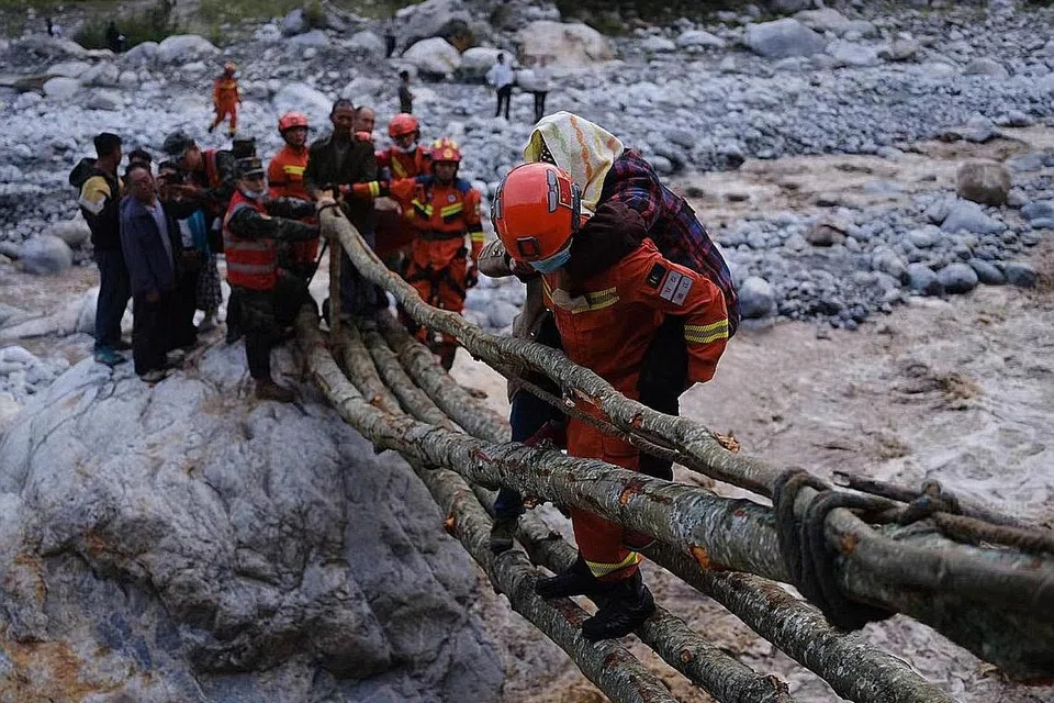 HULUR BANTUAN: Pekerja penyelamat memindahkan penduduk di daerah Luding, pusat gempa kuat yang melanda China kelmarin. Sekurang-kurangnya 46 orang terbunuh sejauh ini. - Foto EPA-EFE